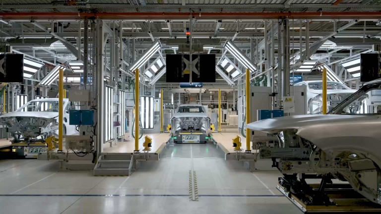 Front-facing view of the unpainted MINI Countryman body shell as it goes through the inspection process, mounted on a mobile robot.